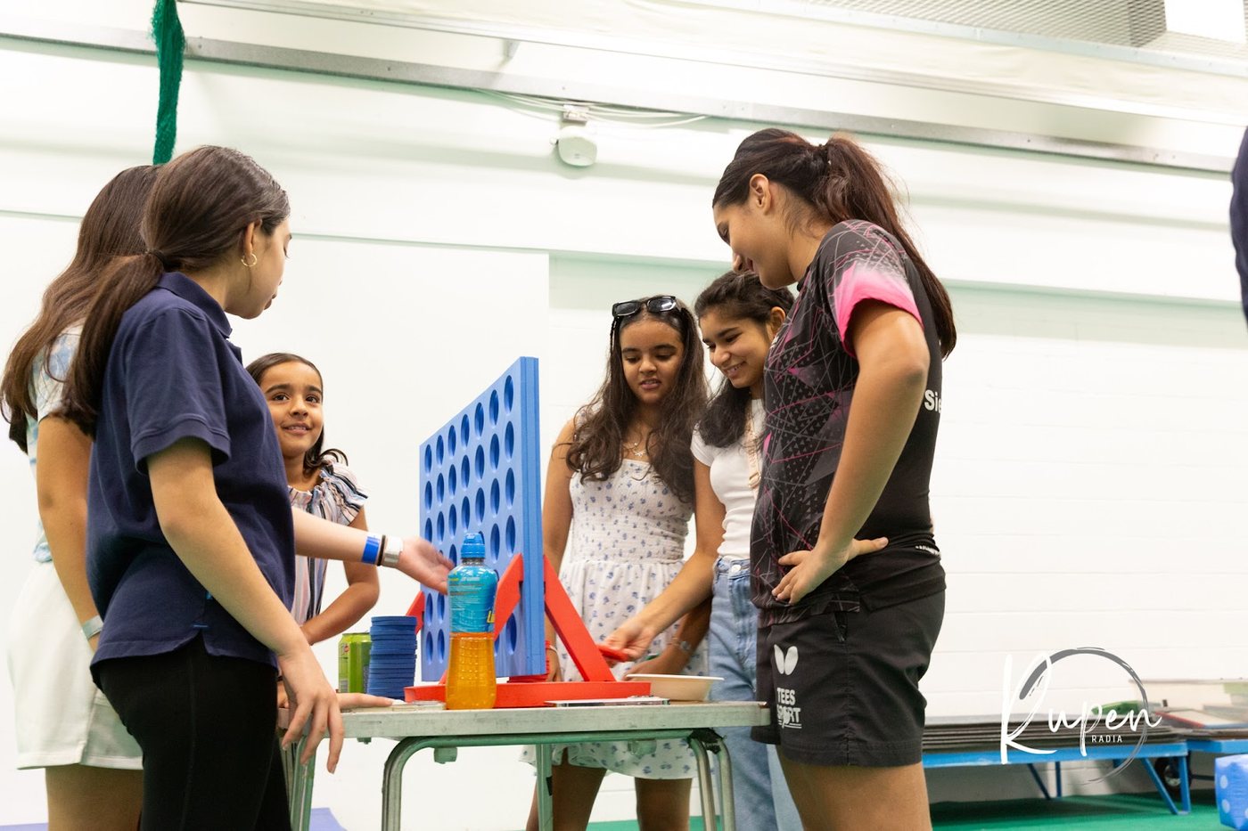 Teenagers gathered around a giant Connect Four game