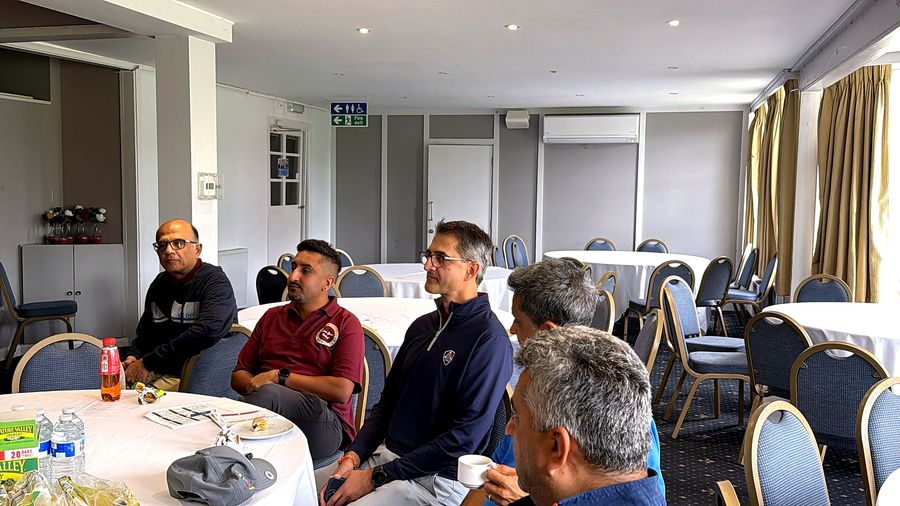 Golfers seated at a table listening to the briefing before the first tee