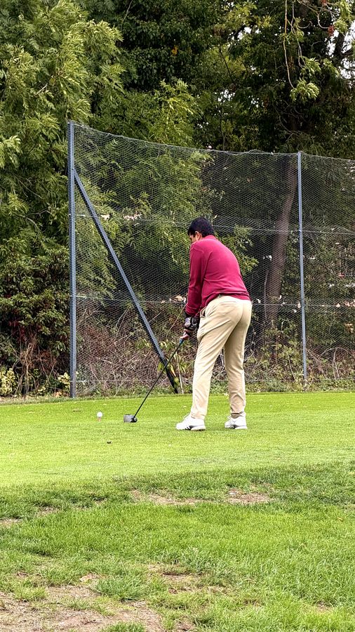 A golfer in a maroon polo mid-swing on the tee at Stanmore Golf Club