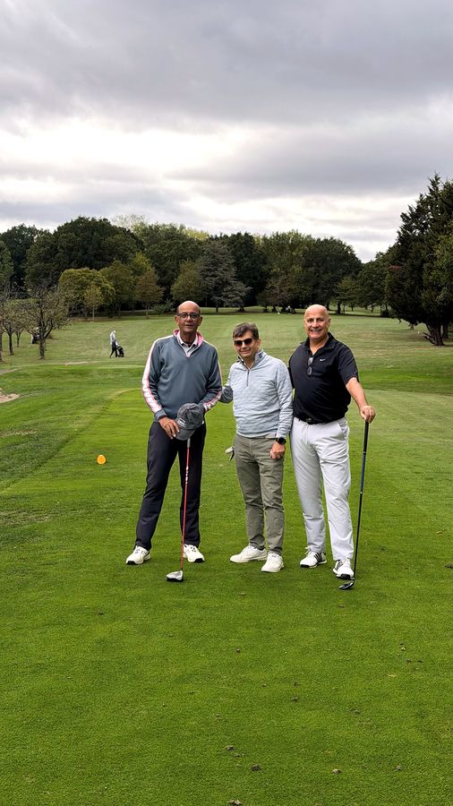 Golfers walking the fairway at Stanmore Golf Club under a wide cloudy sky