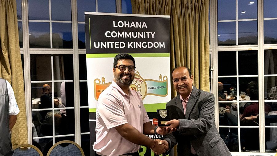 A Golf Day winner in a pink polo shirt receiving his trophy at the presentation