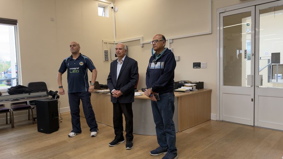 Three Lohana Sports Festival committee members standing at the registration desk in Harrow