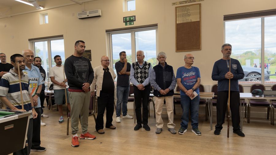 A line of pool players standing along the wall of the hall in Harrow before play starts