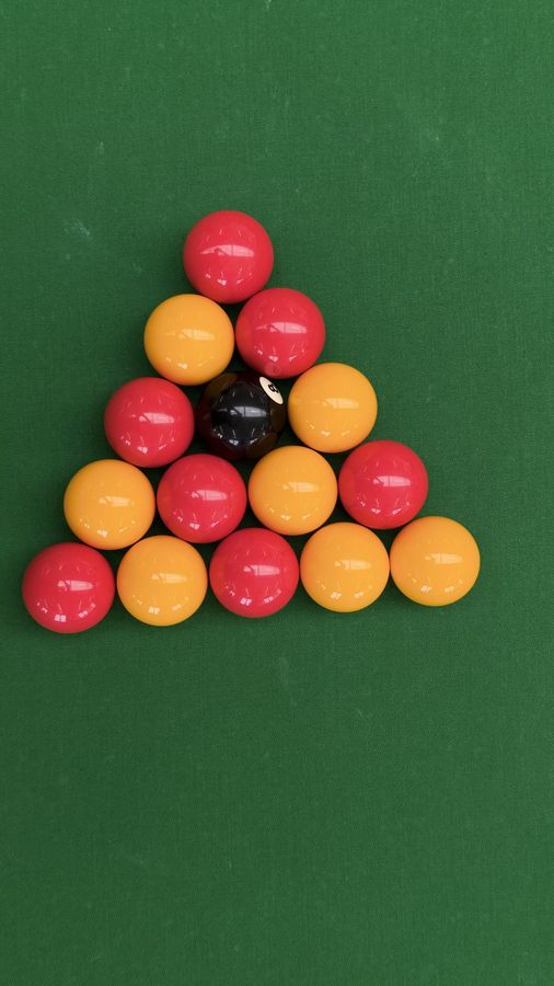 Seven red and seven yellow pool balls with the black, racked and photographed from above