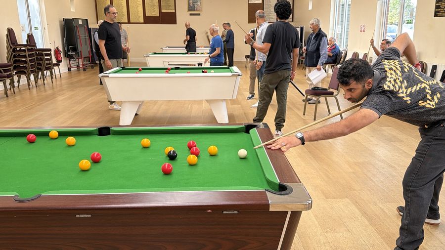 A player reaching across a pool table to play a shot in the Under 50 singles