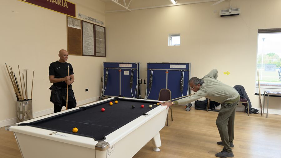 An Over 50 player lining up a shot on a black-cloth pool table at the RCT Centre in Harrow